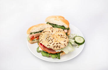 Sandwiches made of crunchy bread rolls, with fresh vegetables and Polish meat cold cuts, on a white plate, isolated.