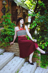 Fashion portrait of young, happy, elegant redhead curly woman, girl in hat and casual clothes. French style. Walking, relax in the city street. Sunny day.
