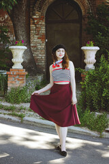 Fashion portrait of young, happy, elegant redhead curly woman, girl in hat and casual clothes. French style. Walking, relax in the city street. Sunny day.