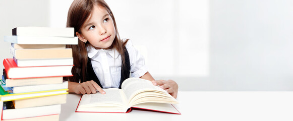 Young cute girl sitting at the table and reading a book - 540964656