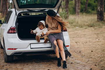 Mother with her son sitting in trunk of car in forest  