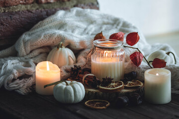 Autumn home composition with aromatic candle, dry citrus, cinnamon, anise. Aromatherapy on a grey fall morning, atmosphere of cosiness and relax. Wooden background close up