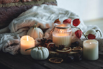 Obraz na płótnie Canvas Autumn home composition with aromatic candle, dry citrus, cinnamon, anise. Aromatherapy on a grey fall morning, atmosphere of cosiness and relax. Wooden background close up