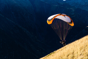A paraglider launching in the dark valley in the Alps