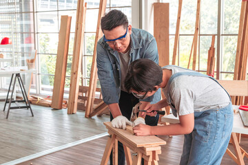 Attentive carpenter is teaching his son.