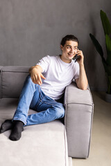 Young man sitting relaxed on sofa and talking on the phone