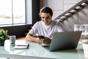 Fototapeta premium Portrait of a man looking at smart phone sitting at table at home.