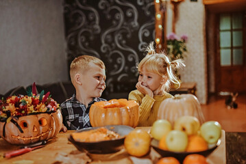 Boy and girl fool around decorating Halloween pumpkins.