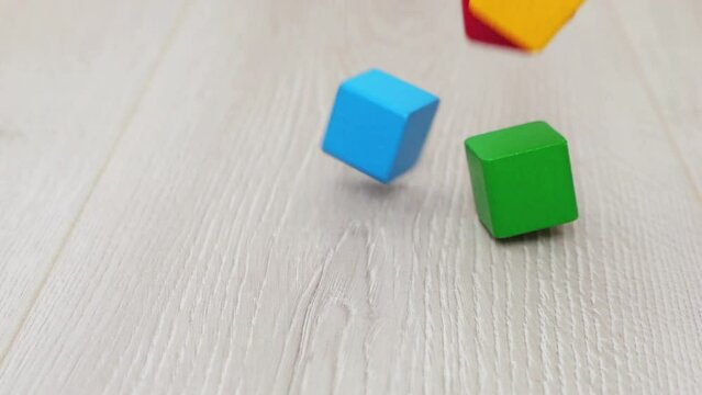 Children's play wooden toy blocks fall to the floor. Slow motion.