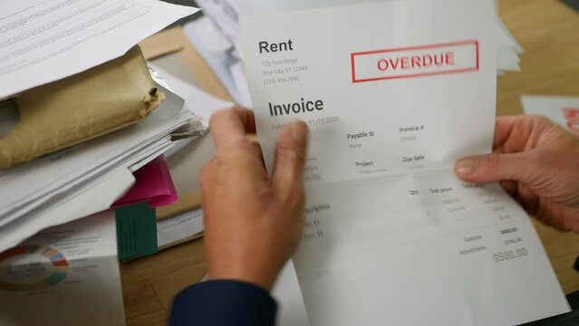 Close up of a man opening debt letters. The letter shows a rent overdue notice