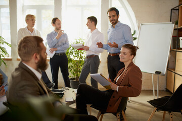 Group of young people, businessmen at business meeting at office space. Scientific conference event, training, brainstorm.