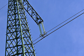 The top of the transmission tower for electrical transmission line. Close-up with glass disk insulators and electric cables. 