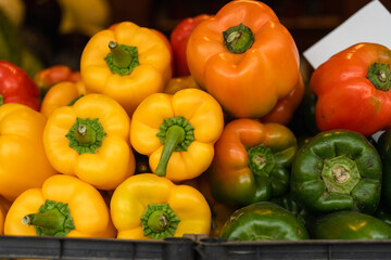 Close-up ripe organic natural yellow, red and green peppers on a street vegetable stall, sweet pepper background image, soft focus