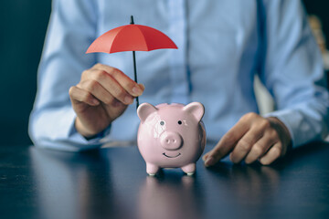 Piggy bank and woman holding red umbrella Protect assets and save money on health insurance...