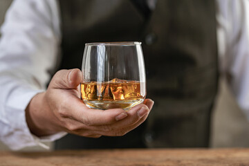 
Close-up of serious businessman holding whiskey glass shows concept of executive privilege. Soft focus. Close-up view of two men in formal wear whiskey clashing glasses.