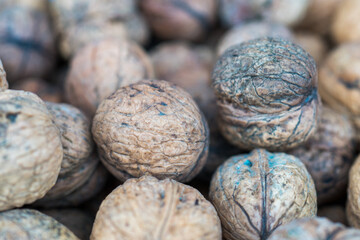 Close-up of ripe walnuts in the shell on the counter of the store, harvesting the autumn harvest of nuts, macro photography, soft selective focus
