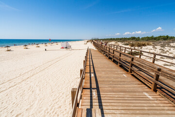 Wide sandy beach with wooden bridges along dunes in Monte Gordo, Algarve, Portugal