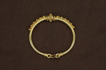 gold bangle on red-brown cloth background