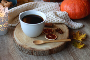 Cup of tea or coffee, seasonal spices, bowl of cookies, blanket, pumpkins, colorful leaves, books and candle. Cozy autumnal atmosphere at home. Selective focus.