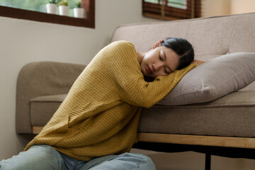 Asian woman with a headache and stress while sitting on the sofa at home