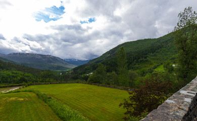 Fototapeta na wymiar Beautiful Lush Green Summer Mountain View Of The Naeroy Valley With Overcast Sky At Stalheim Hotel In Vossestrand, Western Norway.