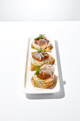 Aesthetic composition with tomato bruschetta on white background with harsh shadows. Italian bruschetta with tomatoes and cheese on fine dining in summer. Elegant menu concept.
