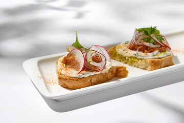 Aesthetic composition with tomato bruschetta on white background with harsh shadows. Italian bruschetta with tomatoes and cheese on fine dining in summer. Elegant menu concept.