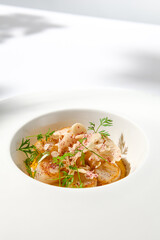 Appetizer with roasted sea scallop and cauliflower. Creamy risotto with scallops and vegetables. Grilled sea scallops in white ceramic plate with harsh shadows. Seafood menu. Summer food.