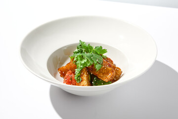 Crispy eggplant in chinese style on white plate. Crispy eggplant salad on summer menu. Asian appetizer - roasted aubergine with coriander leaves. Vegan food. Aesthetic veggie menu.