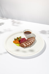 Roast duck fillet with vegetables puree and sauce on light background. Elegant dish from duck fillet and vegetables in summer menu Roasted and sliced duck breast with gravy on white plate