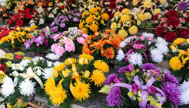 Bunches of artificial flowers on graves. Colorful flower wreaths. Remembering the Dead.
