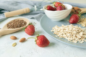 Oatmeal, fresh strawberries on a plate, raisins, nuts and seeds, on the table, healthy breakfast ingredients