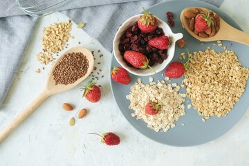Oatmeal, fresh strawberries on a plate, raisins, nuts and seeds, on the table, healthy breakfast ingredients