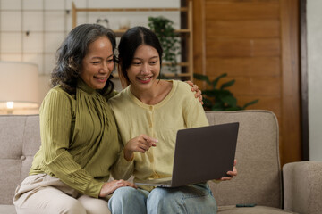 Asian mature woman hugging with daughter while sitting on sofa, mother day concept.