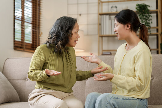 Asian Mature Mom And Adult Daughter Have Fight At Home While Sitting On Sofa.