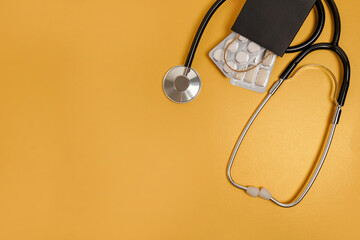 Stethoscope with pills in black paper bag on golden background, copy space , black friday, medicine