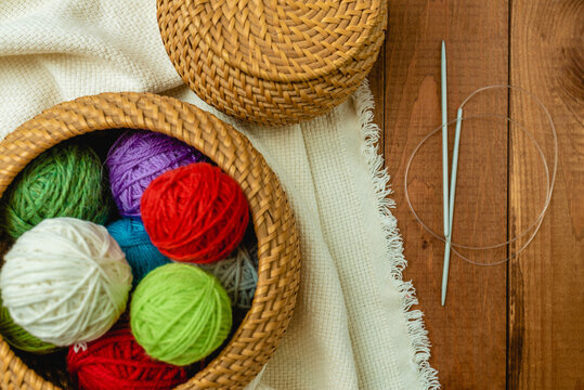 Yarn in a basket. Colorful balls of wool on wooden table. Variety of yarn balls, view from above.