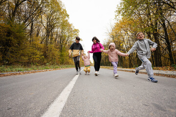 Obraz premium Mother with four kids running on road at autumn fall forest.