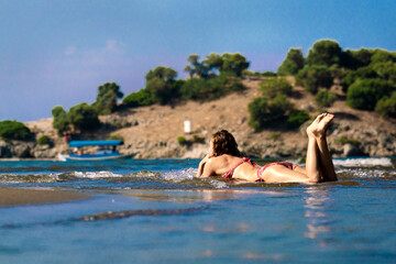 A woman is sunbathing in the waves of the sea surf. Happy vacation in nature