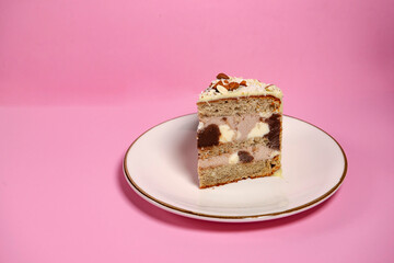 Festive banana cake in white chocolate, decorated with nuts, cookies and chocolate on a pink background. exclusive pastries, author's recipes. copy space. for a culinary blog and a pastry shop