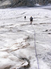 Hikers traveling on the white glacier in the Alps