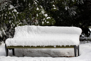 pack bench under snow as the snow continues to fall for a wintery scene