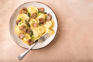 Ravioli with mushrooms and mushroom filling with fragrant herbs and ground pepper on a delicate peach beige background. Winter recipes for the cold season of Italian cuisine, copy space