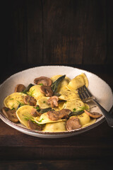 Ravioli with mushrooms and mushroom filling with fragrant herbs and ground pepper on the rustic wooden background. Winter recipes for the cold season of Italian cuisine, close-up