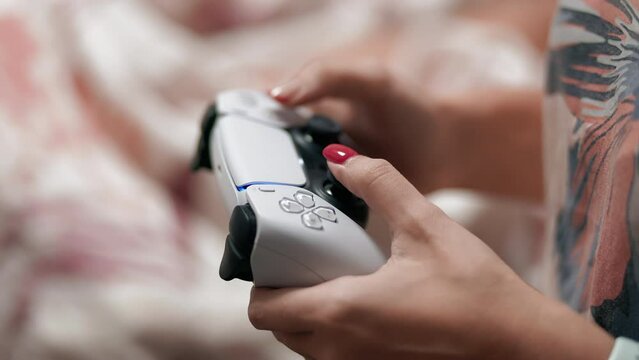 Young woman's hands holding a modern video console controller playing a game