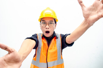 Portrait of a joyful male construction worker or engineer taking selfie and holding camera with hands over white background. asian male engineer open arms for a hug and giving surprise gesture.