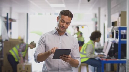 Male Manager In Busy Logistics Distribution Warehouse Using Digital Tablet