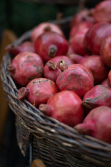 Harvest of ripe pomegranate in wicker baskets at outdoor farmers market in Tbilisi Georgia. Vegetarian healthy food