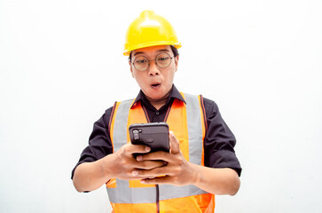 excited asian male construction worker, engineer, architect in orange vest and yellow safety hardhat holding phone with happy euphoric shocked wow expression. billboard model advertisment concept.
