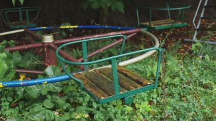 Creepy Abandoned Ruined Playground with Slide and Withered Wooden Seat on Rusty Metal Carousel